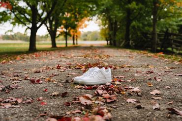 White basketball shoes on a long laneway lined with trees in the fall.