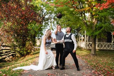 Bride and groom in basketball jerseys jump for the ball tossed by the officiant in a ref jersey.