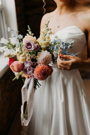 Bride holding her wildflower bouquet and admiring the colours.