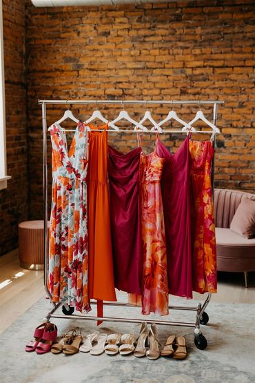 Bridesmaids gowns hanging on a rack with their shoes lined up underneith.
