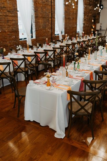 Wedding Ceremony rectangular dining tables, with two tone pink and peach napkins and candles.