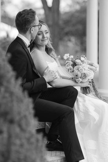 Black and white photo of a Bride and groom enjoying some quiet time while they sit on the porch.