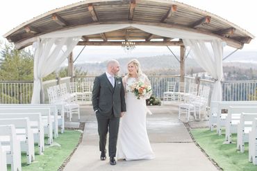 Newlyweds walking up the Belvedere ceremony aisle, arms linked, smiling at each other.