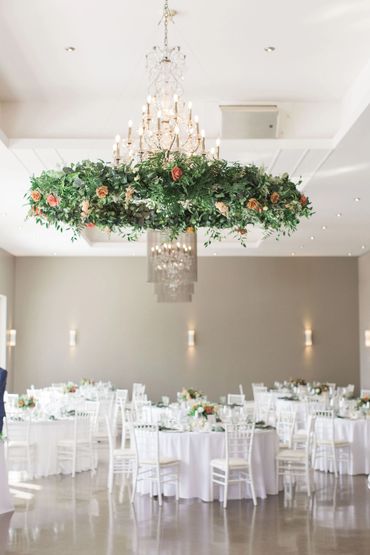 Stunning round, ceiling floral install over dance floor and tables draped in white.