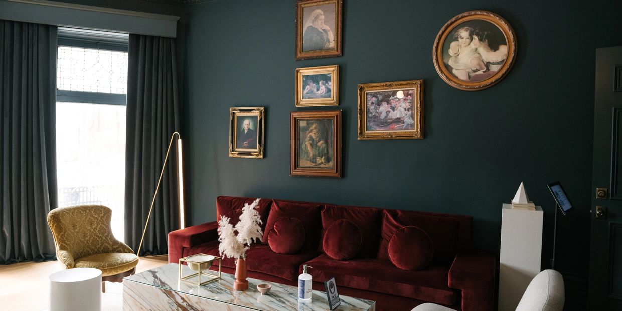 Common area at the Rosemount Inn. Dark green walls, a burgundy soft, marble table and yellow chair.