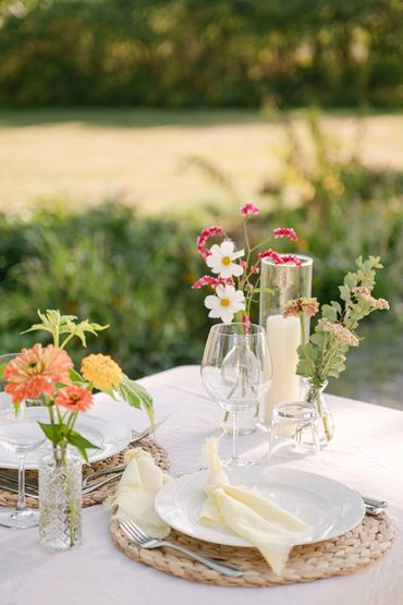 Alfesco place setting with summer florals, water hyacinth chargers and light yellow napkins.