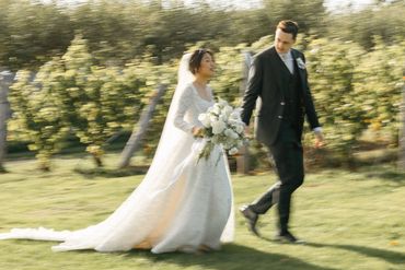 Bride and groom doing sunset photos while walking through in a vineyard.