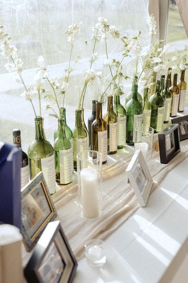 Wine bottle seating chart with wild flowers popping out of the tops of them.