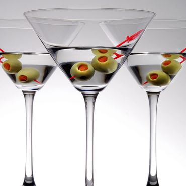 Three martini glasses with olives on red picks.