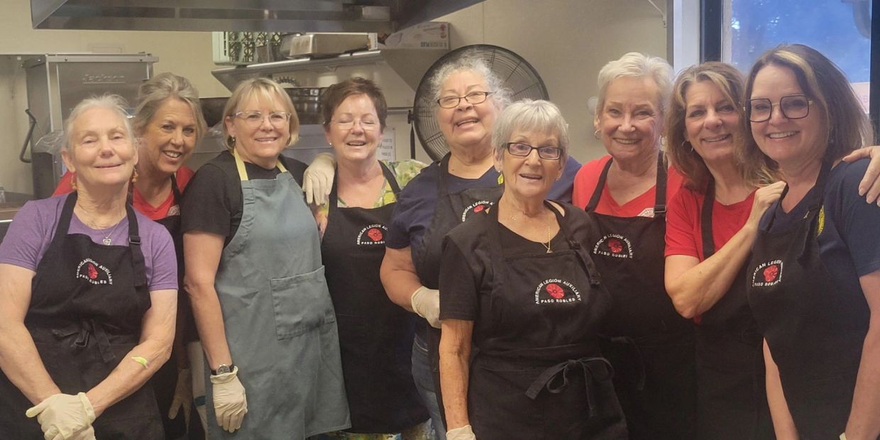 Group of women volunteers in aprons smiling.