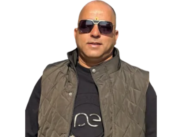 Man wearing sunglasses and a quilted vest posing confidently.