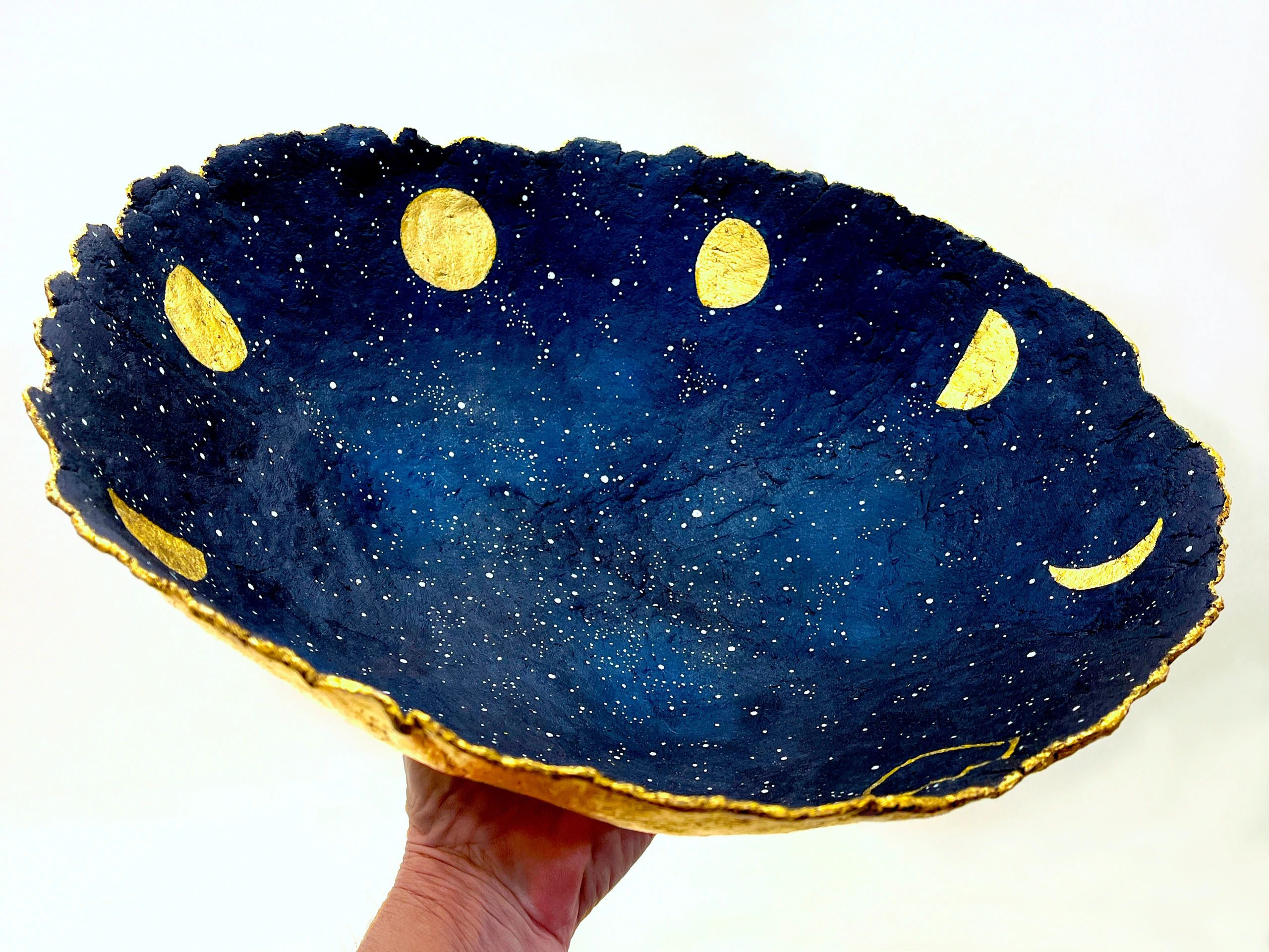 Paper clay bowl, moon phases, starry sky, gold leaf, deep blue star field, nature, surreal, ritual o