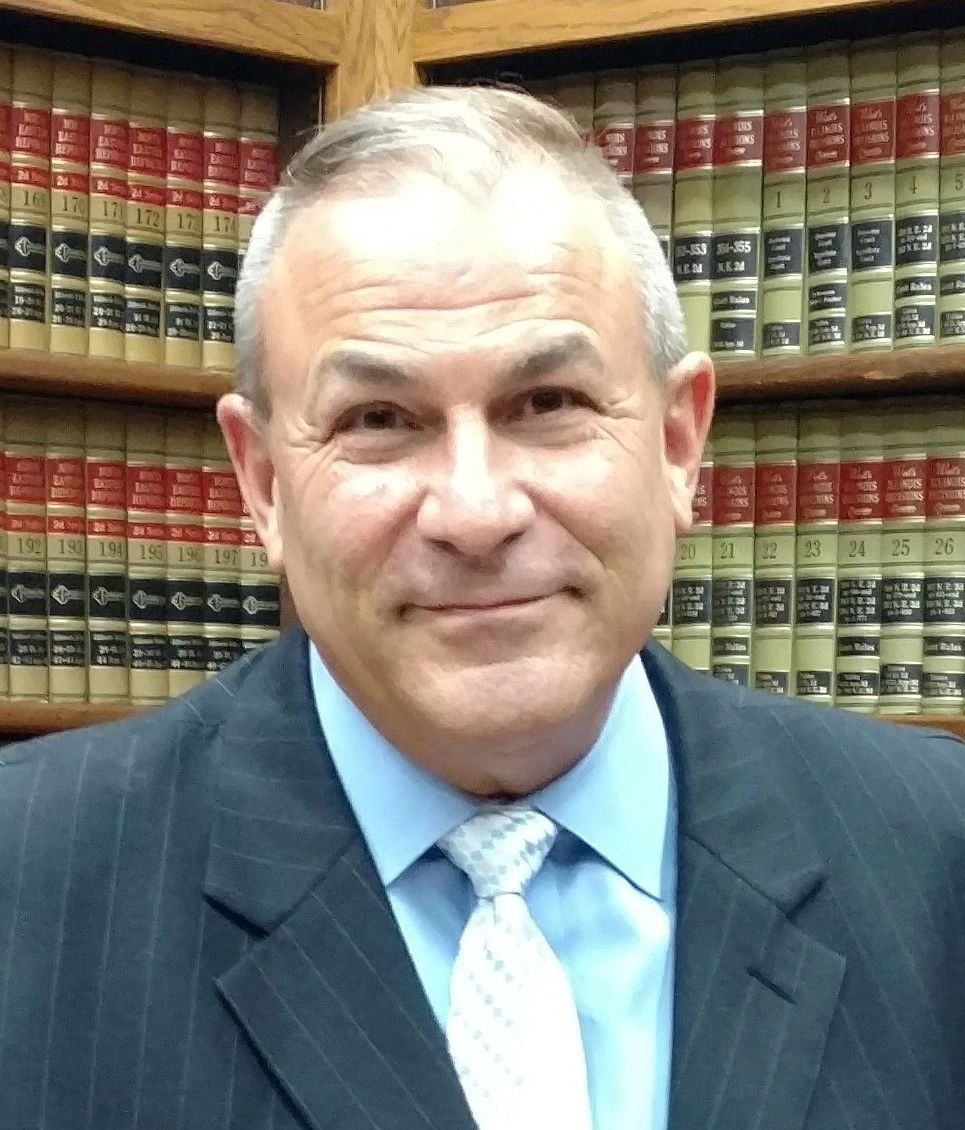 Middle-aged man in suit with law books background.