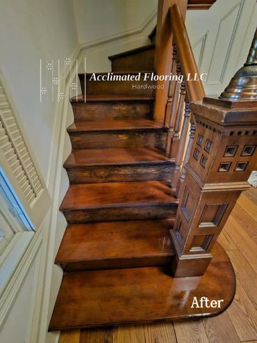 Restored hardwood stairs with a rich, polished finish and intricate woodwork on the banister.