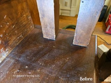 Close-up of worn, dusty hardwood floor under furniture legs before cleaning.
