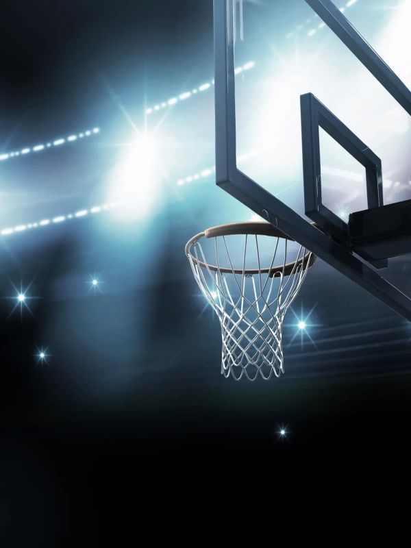Basketball hoop illuminated by stadium lights.