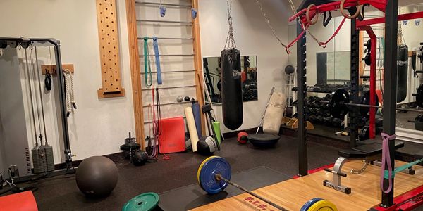 Strength training area at TIS Fitness Systems in Denver with a power rack, wall bars, heavy bag, and