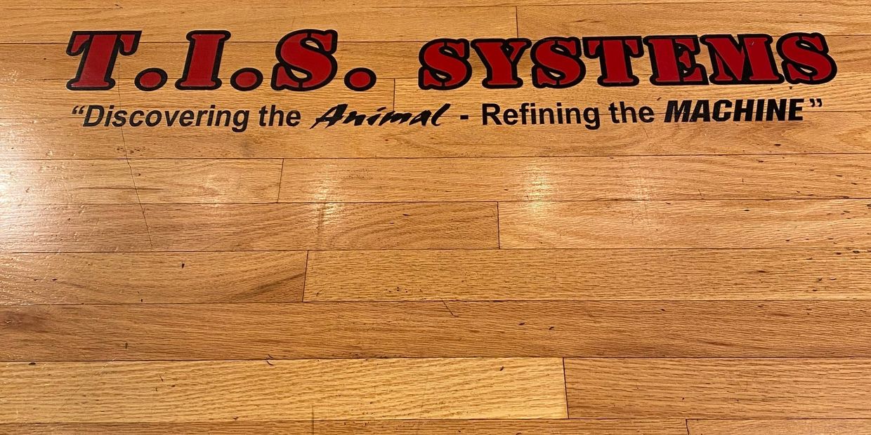 T.I.S. Systems logo and tagline Discovering the Animal, Refining the Machine on the hardwood lifting