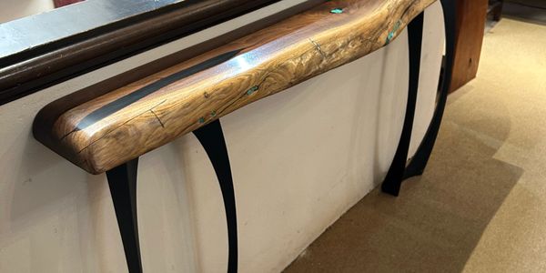Elegant wooden console table with curved black metal legs and natural wood grain top.