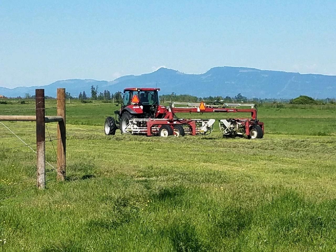 Out on the farm with the big case tractor raking hay into rows getting ready to start baling. 