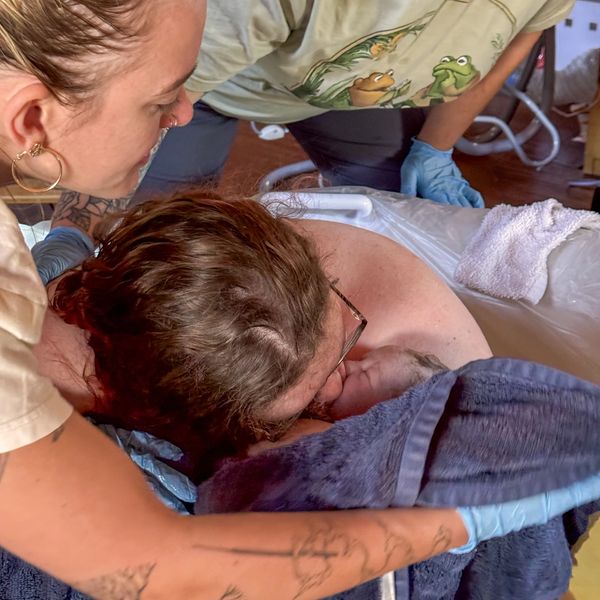 Woman holds newborn baby after birth at home.