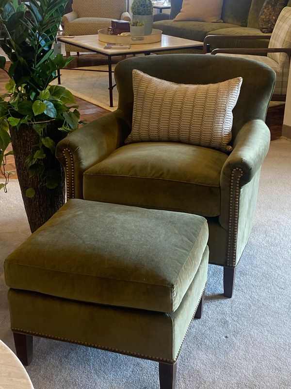Green velvet armchair with matching ottoman in a cozy living room.