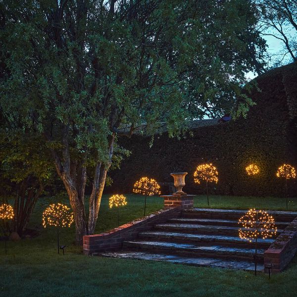 Outdoor garden lights shaped like glowing dandelions illuminate steps at dusk.