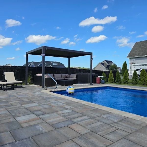 Backyard pool area with lounge chairs and shaded seating.