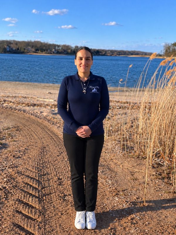 Woman standing on a sandy beach near the water.