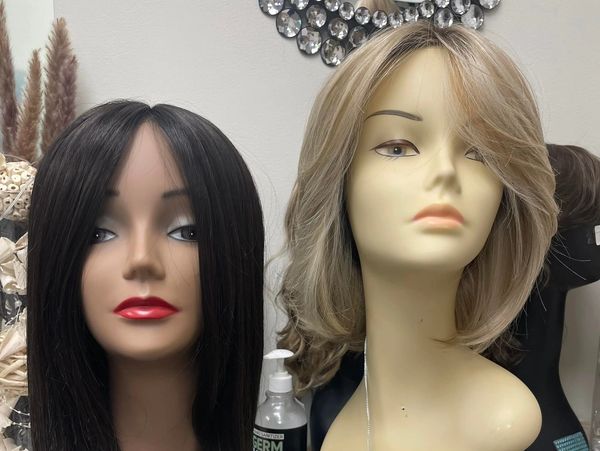 Two mannequin heads with different wigs displayed in a salon setting.