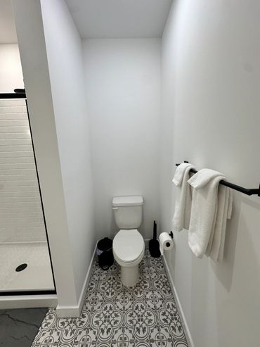 Minimalist bathroom with patterned floor tiles and white walls.