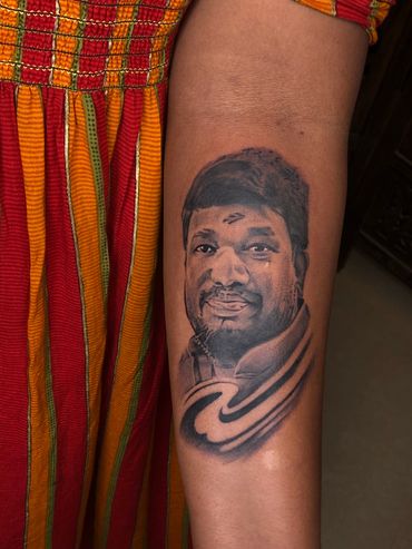 Realistic black and gray portrait tattoo on forearm.