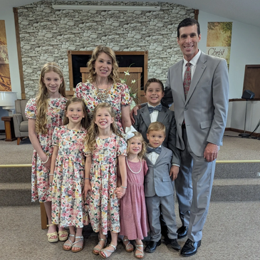 Family dressed formally in a church setting, smiling together.