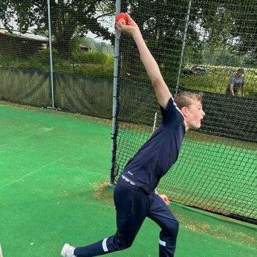 a boy bowling a cricket ball with a look of determination in his face.
