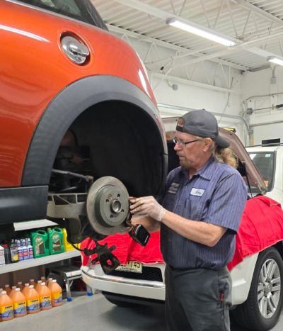 Mécanicien travaillant sur les freins d'une voiture rouge levée.