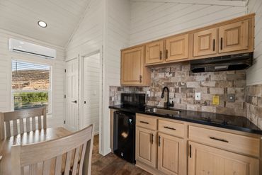 Cozy kitchen with light wood cabinets, black appliances, and a dining area with natural light.