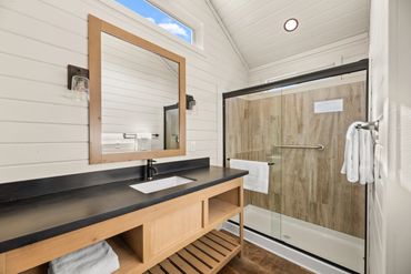 Modern bathroom with wood accents and glass shower enclosure.