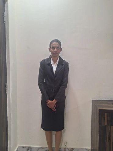 Professional woman in a black suit standing against a plain wall.