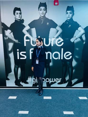 A woman stands confidently in front of a 'Future is female' poster.