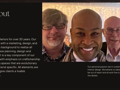 Three men smiling together in front of string lights.