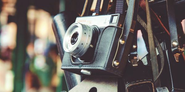 Vintage cameras in leather cases hanging together.