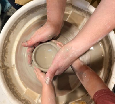 Hands shaping pottery on a wheel.