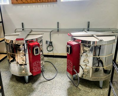 Two shiny pottery kilns with digital controllers in a workshop.