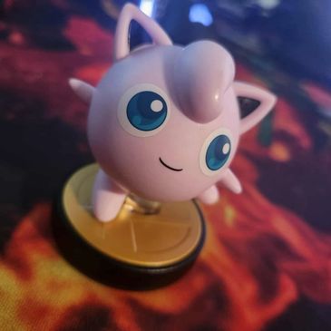A cute Jigglypuff figurine on a fiery background.