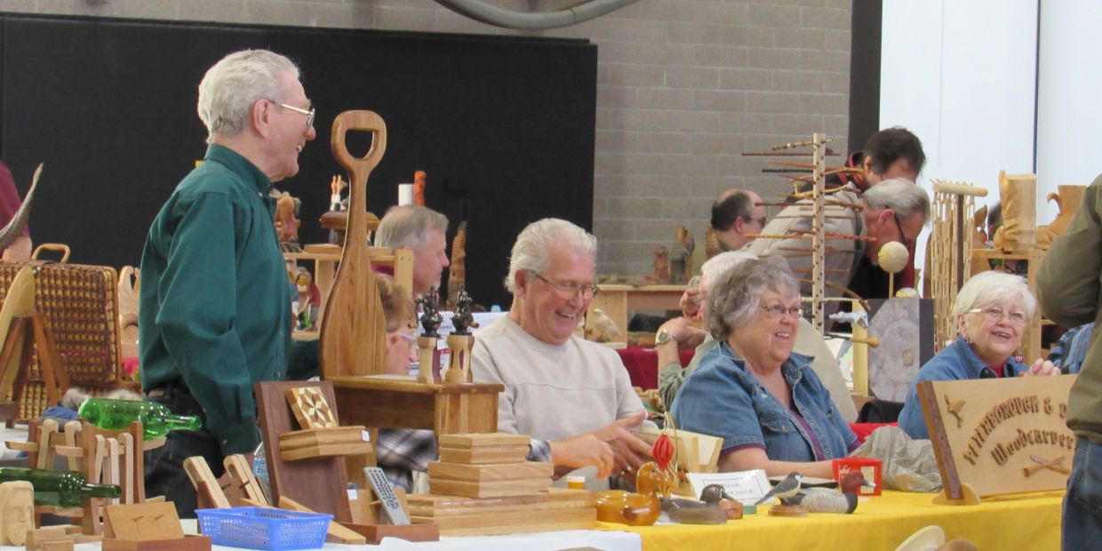 Smiling woodcarvers at a carving show.