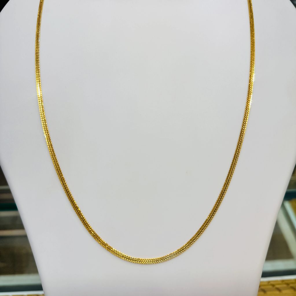Elegant gold chain necklace displayed on a white stand.