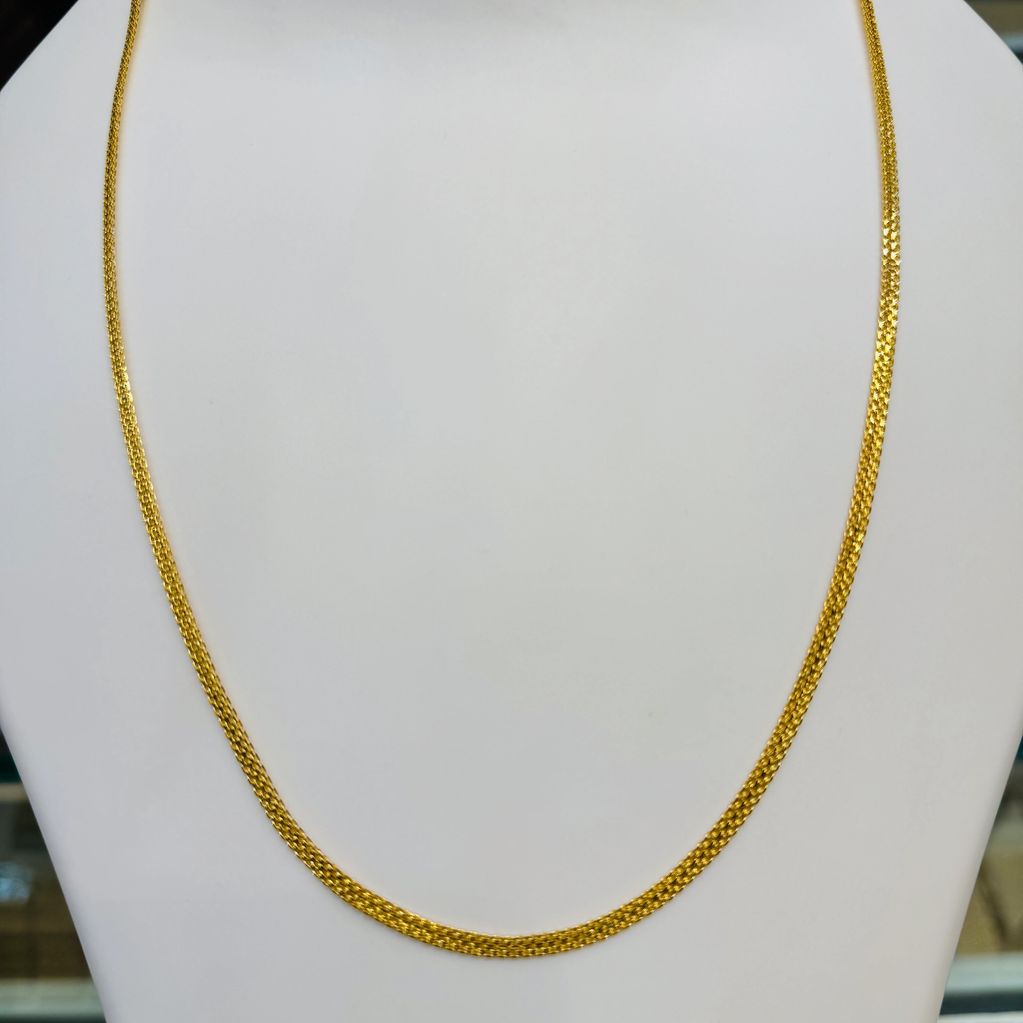 Elegant gold chain necklace displayed on a white bust stand.