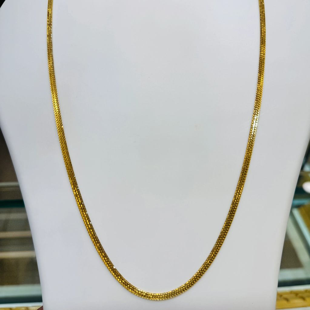 Elegant gold chain necklace displayed on a white stand.