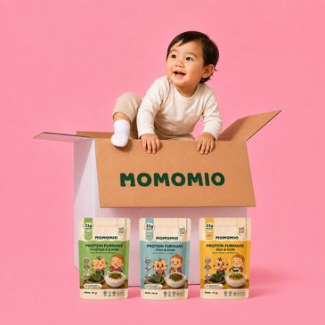 Happy baby playing in a Momomio box with three protein furiake packs.