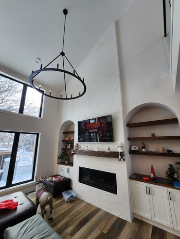 Elegant, sophisticated living room with European arched shelves. Micro cement accent wall, fireplace.